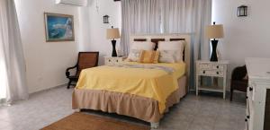a bedroom with a bed with a yellow bedspread at Villas Del Jardin 7 in Juan Dolio +30 photos