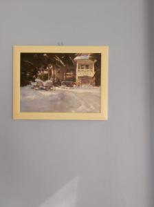 a framed picture of a house in the snow at Fehér Hintó in Miskolctapolca