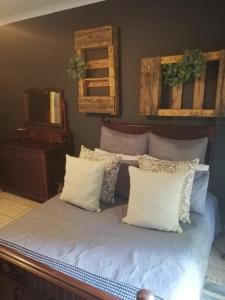 a bedroom with a bed with white pillows and a mirror at A-Cody Place in Louis Trichardt