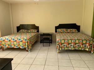 a bedroom with two beds and a table with a chair at ThA LaGooN SpOt Caribbean BrEeZe in Port Antonio