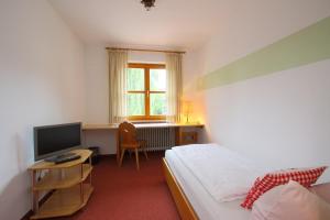 a bedroom with a bed and a desk with a television at Gasthof Rundeck 