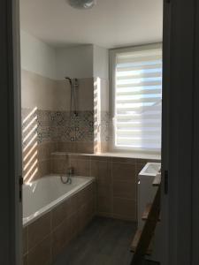 a bathroom with a tub and a window at La belle Epoque in Damparis