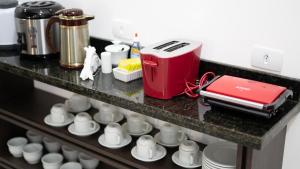 eine Theke mit Tassen und einem Toaster darauf in der Unterkunft Hotel Carmelo in São José dos Pinhais