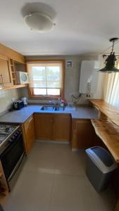 a kitchen with wooden cabinets and a sink and a window at Samay Huasi - 3 dorm en suite - inmejorable ubicación - cochera cub in San Martín de los Andes