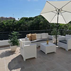 eine Terrasse mit weißen Möbeln und einem Sonnenschirm in der Unterkunft Villas Del Jardin 7 in Juan Dolio