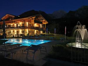 ein Haus mit einem Brunnen vor einem Gebäude in der Unterkunft Gästehaus Obersulzberglehen in Schönau am Königssee