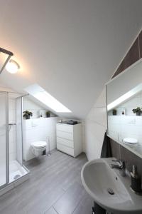 La salle de bains blanche est pourvue d'un lavabo et de toilettes. dans l'établissement Ferienwohnungen Wiesengrund, à Monschau