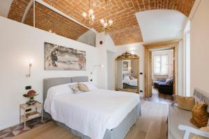 een slaapkamer met een wit bed en een bakstenen muur bij Villa Trisano in Bra
