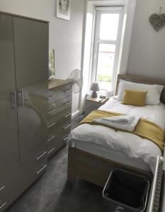 a bedroom with a bed and a dresser and a window at Teviot View Holiday Let’s Hawick in Hawick