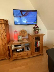 a living room with a wooden entertainment center with a flat screen tv at Ferienwohnung Lara "Im Herzen von Ostfriesland" in Osteel