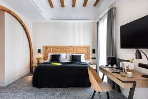 um quarto com uma cama, uma secretária e uma televisão em Cal Roure Boutique Hotel em Igualada