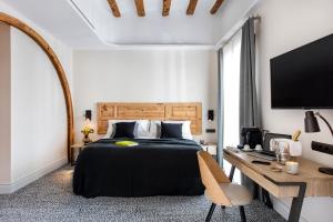 ein Schlafzimmer mit Bett, Schreibtisch und Fernseher in der Unterkunft Cal Roure Boutique Hotel in Igualada