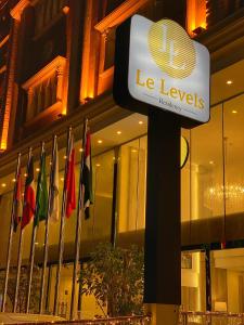 una señal de niveles frente a un edificio con banderas en Le Levels Residency, en Dammam