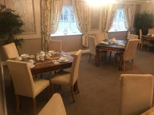 - une salle à manger avec une table, des chaises et des fenêtres dans l'établissement The White Pheasant, à Lenwade