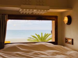 een slaapkamer met een raam met uitzicht op het strand bij GOOD MORNING ZAIMOKUZA in Kamakura