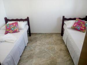 two beds sitting in a room with tile floors at Pousada Pelourinho in Mucuri