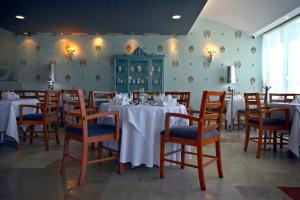 uma sala de jantar com mesas e cadeiras brancas e um quarto com paredes verdes em Rivoli Select Hotel em Veracruz