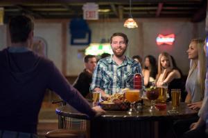 un hombre sentado en una mesa en un bar en Canad Inns Destination Centre Transcona, en Winnipeg