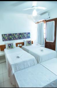 a room with three beds with white sheets at Casa Duplex 3 suítes em Condomínio Fechado in Porto Seguro
