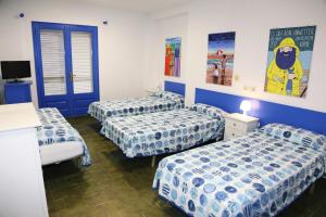 3 camas en una habitación con sábanas azules y blancas en Pensió Solivent, en L'Escala