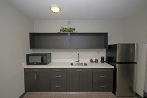 a kitchen with a sink and a microwave and a refrigerator at Clarion Pointe Statesville in Statesville