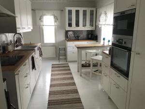 een keuken met witte kasten en een tapijt op de vloer bij Moderni talo Tornion keskustassa in Tornio