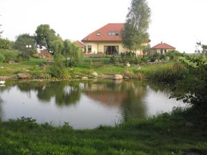 ein Haus neben einem Teich vor einem Haus in der Unterkunft Cichy Zakątek in Krzynowłoga Mała