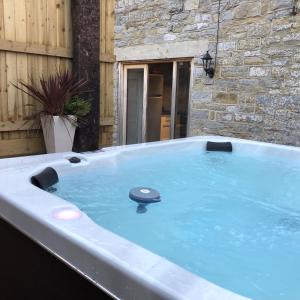 uma banheira de hidromassagem no quintal de uma casa em Somerset Country Escape - Luxury barns with hot tubs em Hatch Beauchamp