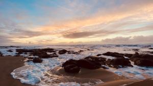 - une plage avec des rochers et l'océan avec un coucher de soleil dans l'établissement Seahorse Oceanfront Lodging, à Lincoln City
