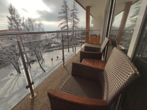 a balcony with two chairs and a view of the snow at Apartmán Hrebienok Rezort A307 in Starý Smokovec