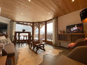 Una sala de estar con un sofá, una mesa y un televisor. en LA PETITE AZALÉE, en Montriond