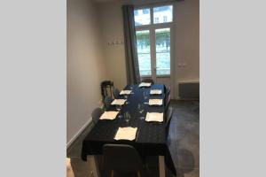 une salle de conférence avec une longue table et des chaises noires dans l'établissement Jolie maison en tuffeau dans le centre de Saumur, à Saumur