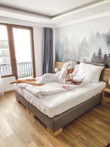 a woman sitting on a bed reading a magazine at SREBRNA PLANINA Spa & Resort in Kopaonik