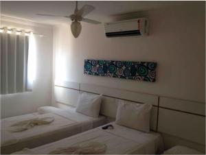a room with two beds and a ceiling fan at Residencial Mont Sião II - Tonziro in Porto Seguro
