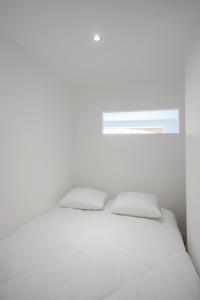 - un lit blanc avec deux oreillers et une fenêtre dans l'établissement Joli T2 bord de mer tout équipé, à Saint-Mandrier-sur-Mer