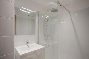La salle de bains blanche est pourvue d'une douche et d'un lavabo. dans l'établissement Joli T2 bord de mer tout équipé, à Saint-Mandrier-sur-Mer