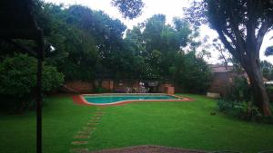 a swimming pool in a yard with green grass at Bottie's Rock in Pretoria
