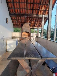 a large wooden table in a room with a brick oven at Vista Panorâmica em São Pedro da Aldeia in Rio de Janeiro