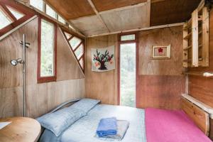 a bedroom with a bed in a room with windows at The Treehut in Island Bay