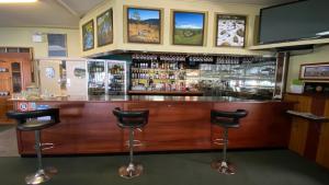 a bar with two stools in a room at Bucketts Way Motel Gloucester in Gloucester