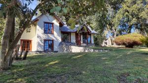 Una casa blanca con un árbol delante. en Cabañas & Aparts Lancuyen, Villa de Montaña en Villa La Angostura