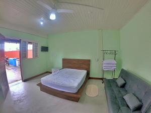 ein Schlafzimmer mit einem Bett und einem Sofa in der Unterkunft Kitnet Com Ar, em frente a Praia de Boracéia in São Paulo
