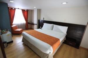um quarto com uma cama grande e uma cadeira em Hotel Plaza Muisca em Tunja