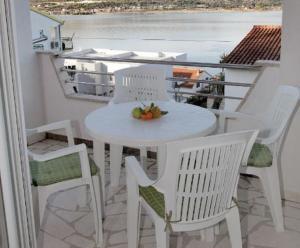 un tavolo bianco con sedie e un cesto di frutta sul balcone. di Apartments Maja - sea view a Trogir