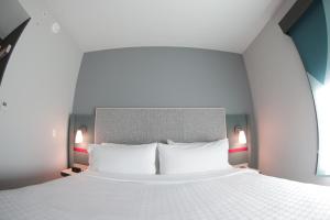 avid hotel - Fresnillo, an IHG Hotel في Fresnillo de González Echeverría: غرفة نوم بسرير ابيض كبير مع وسادتين