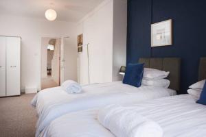 2 camas blancas en una habitación con paredes azules en Newport house sleeps 9 - Mycityhaven, en Newport