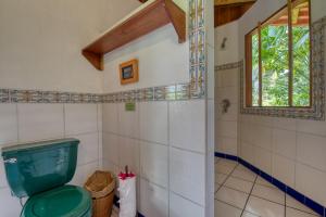 ein Bad mit einem grünen WC und einem Fenster in der Unterkunft Selva Bananito Lodge in Westfalia