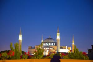 a building with two domes and a mosque at night at White House Hotel Istanbul in Istanbul