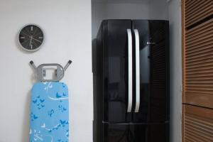 a black refrigerator next to a clock on a wall at Brynglas Newport flat sleeps 8 - Mycityhaven in Newport +35 photos