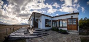 a white house with a wooden walkway in front of it at Estancia Cerro Guido in Torres del Paine